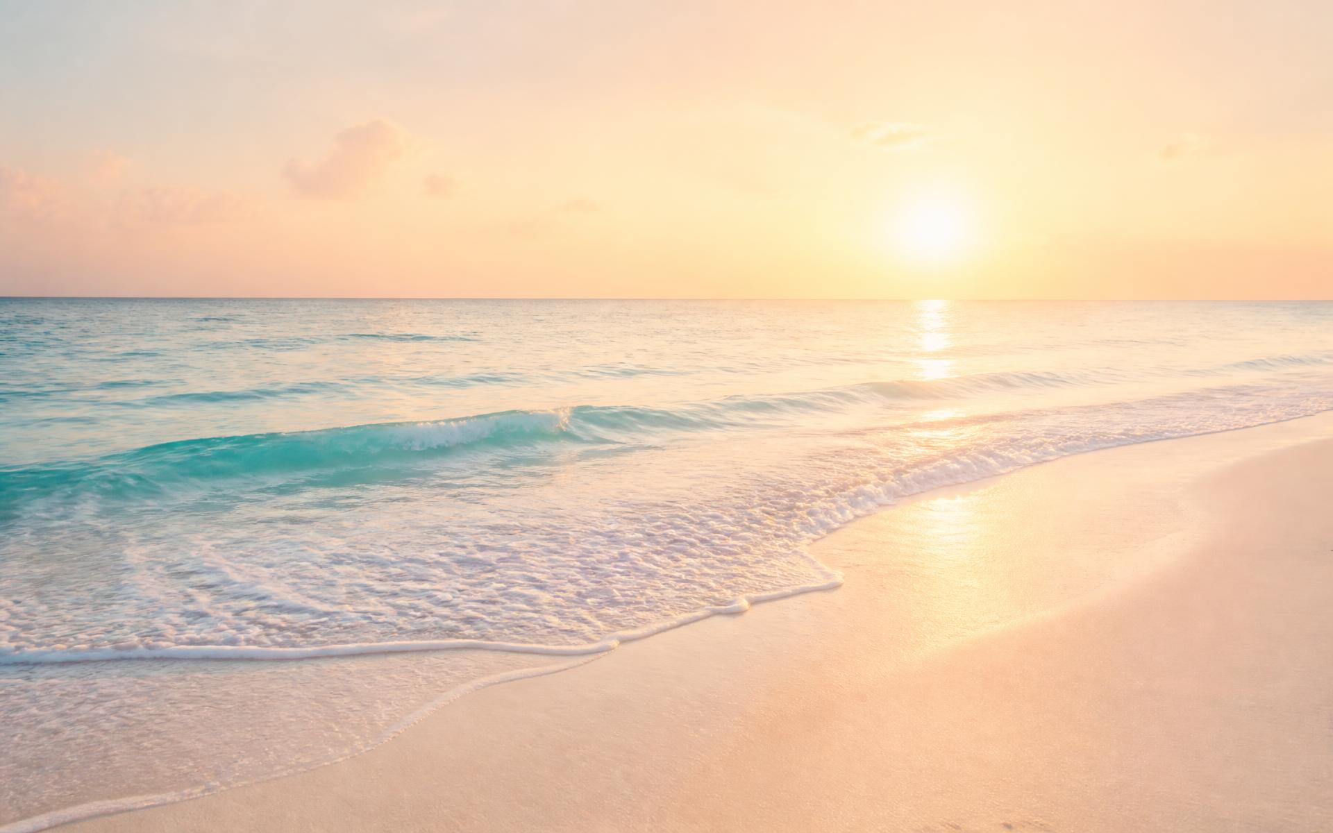 Soft sunlit ocean waves meeting pale sand at golden hour